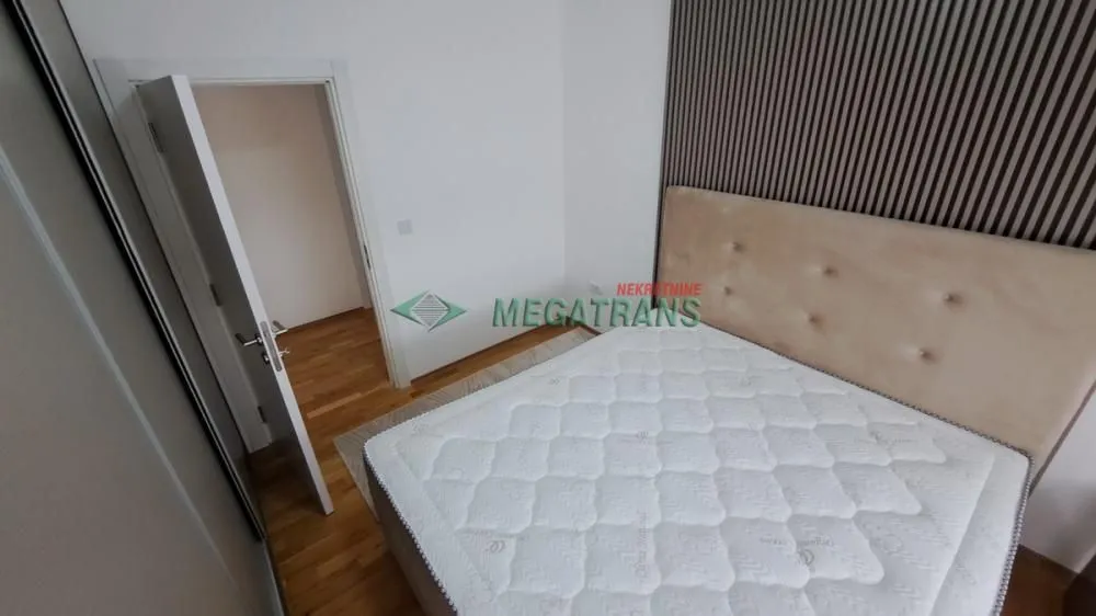 Spavaća soba sa bračnim krevetom i drvenim panelima na zidu.