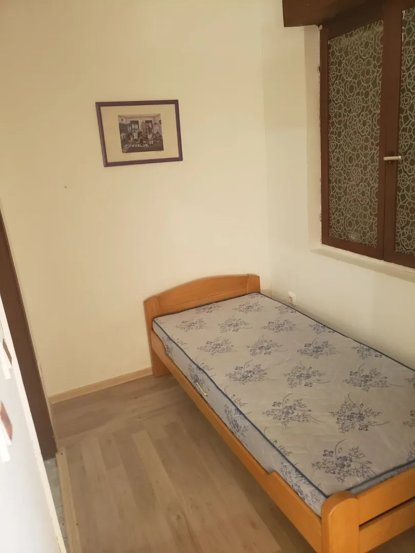 A small bedroom with white walls and a single bed.