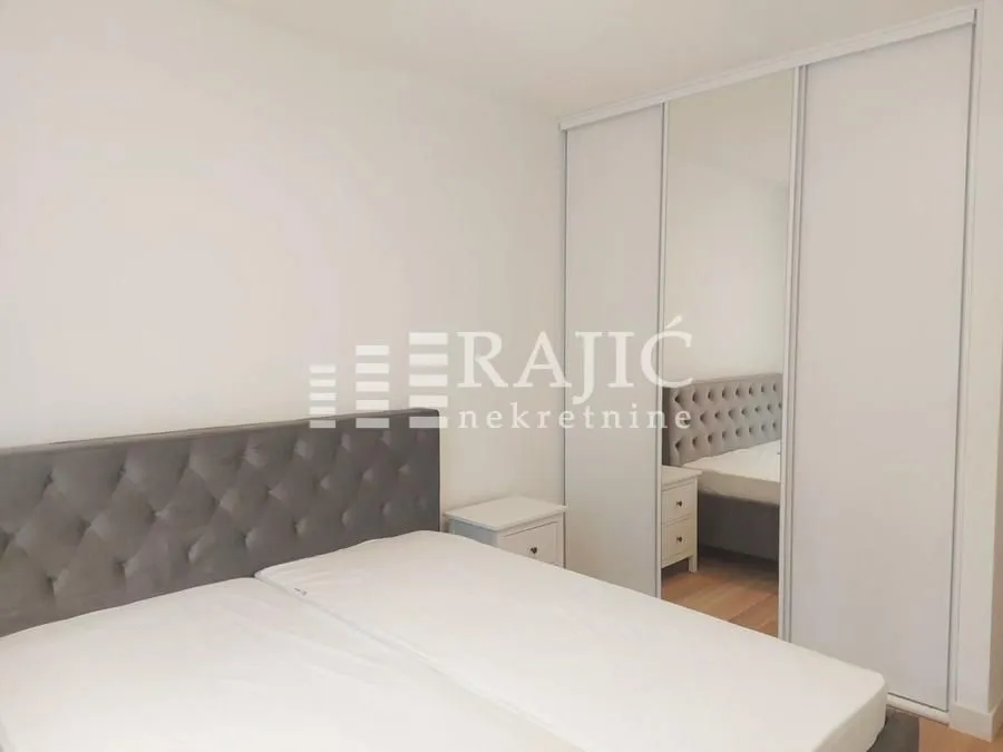 Furnished bedroom with a double bed and a mirrored built-in wardrobe.