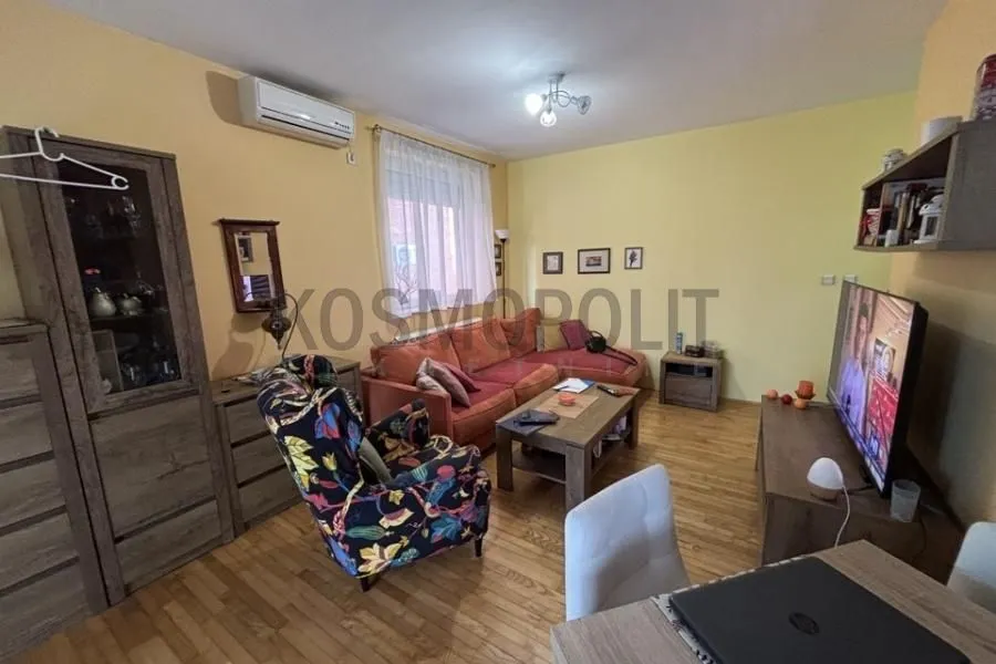 Dnevna soba sa garniturom, foteljom i televizorom.