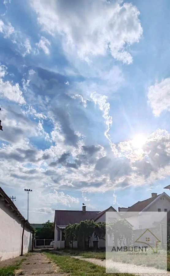 Pogled na dvorište i okolne kuće sa oblačnim nebom.