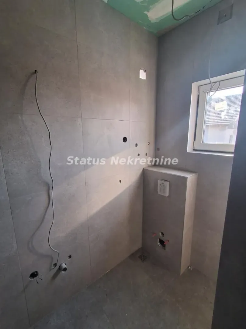 Bathroom under renovation with installed tiles and plumbing infrastructure.