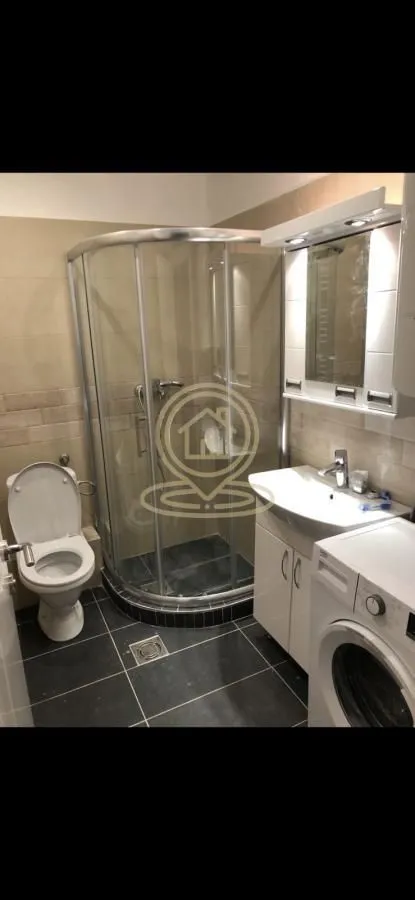 Bathroom equipped with a shower cabin, washbasin, and washing machine.