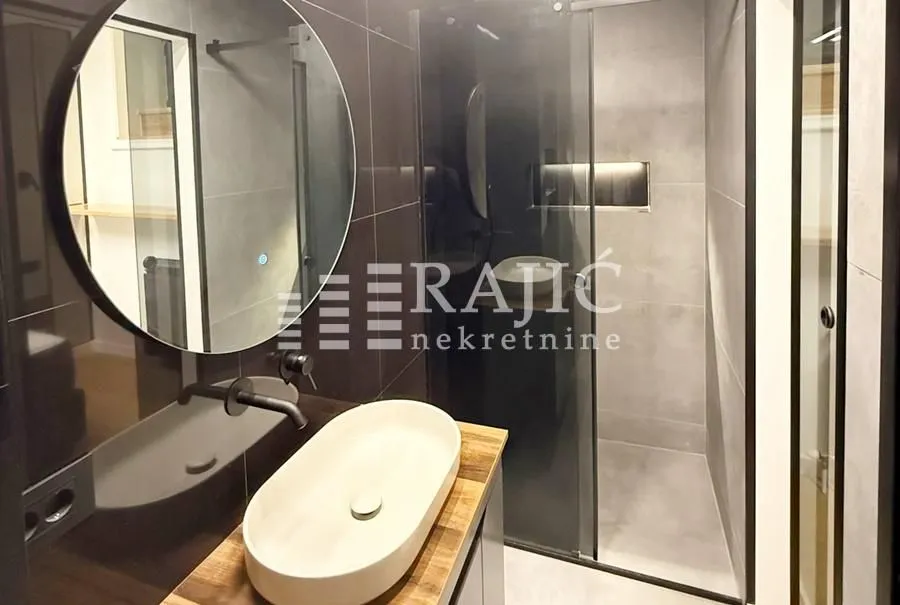 Modern bathroom with a washbasin, mirror, and shower cabin.