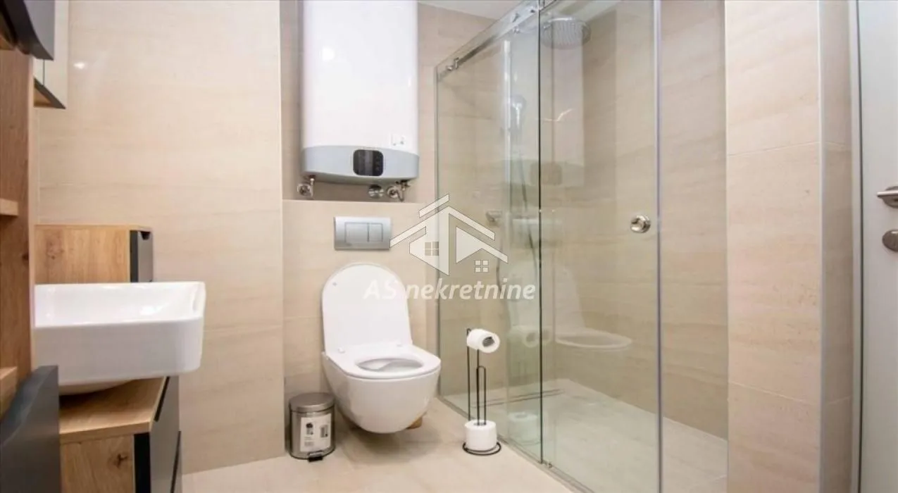 Modern bathroom with a shower cabin, toilet, and washbasin.