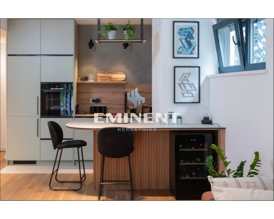 Modern kitchen with a breakfast bar, built-in appliances, and bar stools.