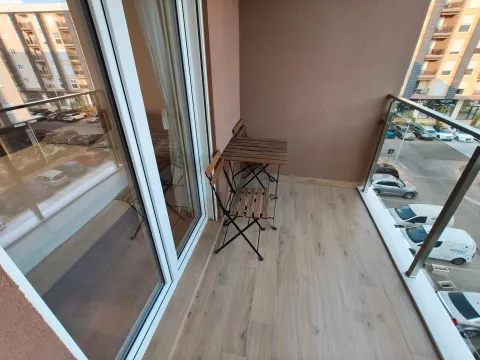 Natkriveni balkon sa drvenim stolom i stolicama i pogledom na parking. - image 12
