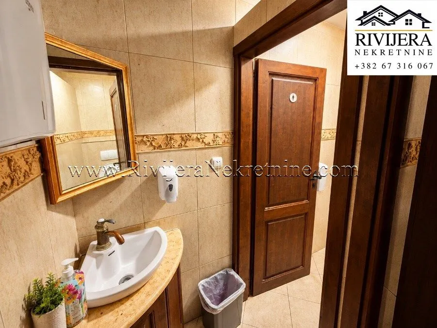 Small bathroom with a washbasin, mirror and wooden door.