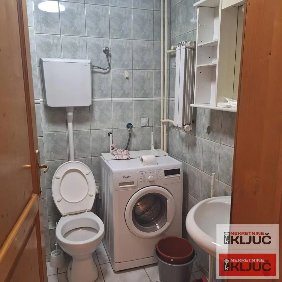 Manje kupatilo sa toaletom, umivaonikom i veš mašinom.