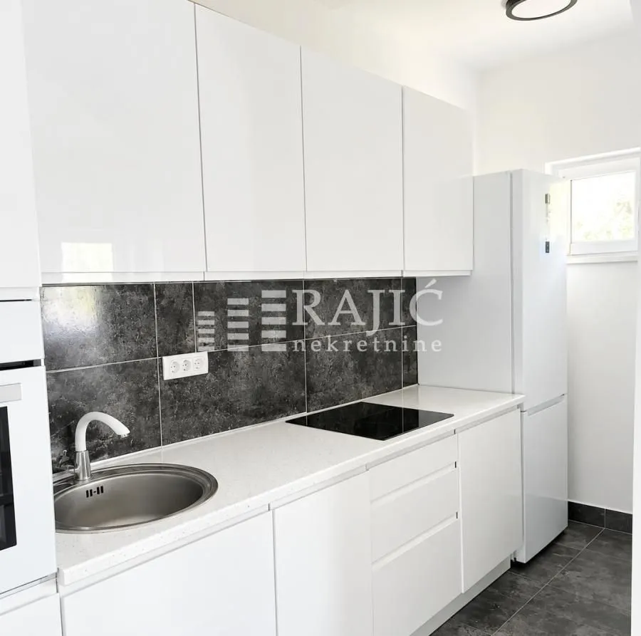 Modern white kitchen with dark countertops.
