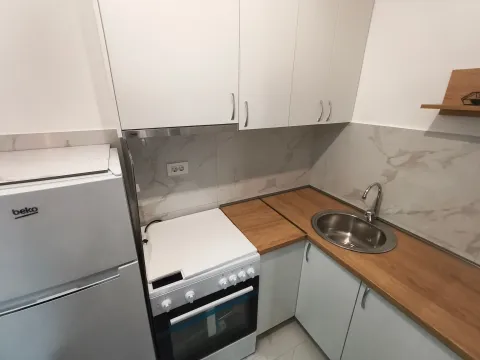 Compact kitchen with white cabinetry, a stove, and a sink. - image 6