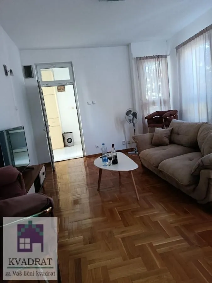 Living room with a sofa, coffee table, and parquet flooring.