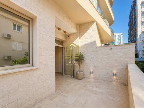Spacious tiled terrace with apartment entrance and a decorative plant. - image 18