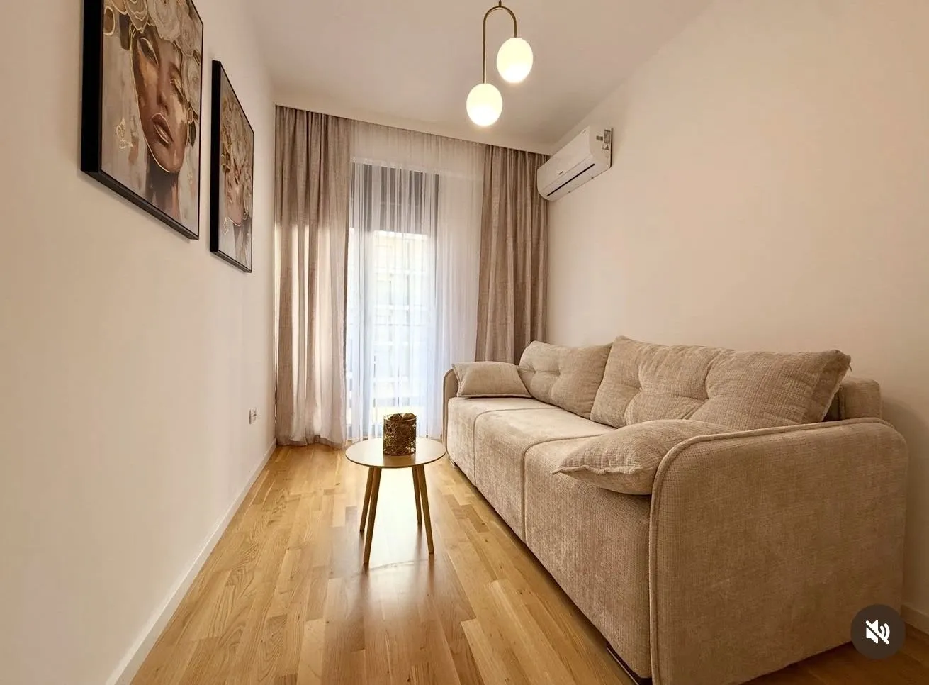 Decorated living room with a beige sofa, wooden flooring, and wall art.