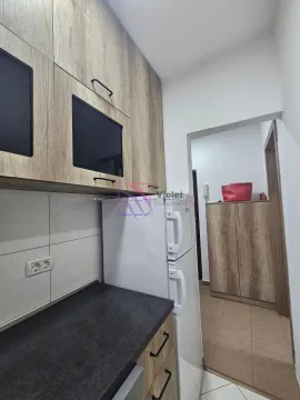Part of the kitchen with wooden cabinets, a refrigerator, and a view of the hallway. - image 12