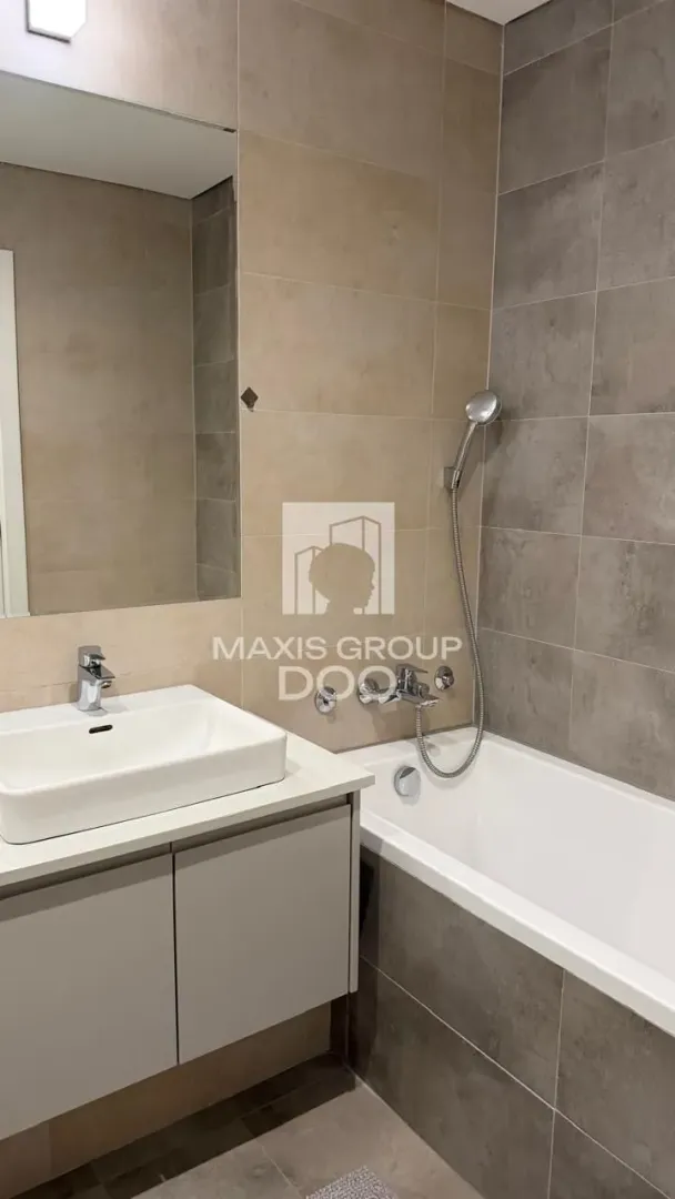 Modern bathroom with a washbasin, mirror, and bathtub with a shower.