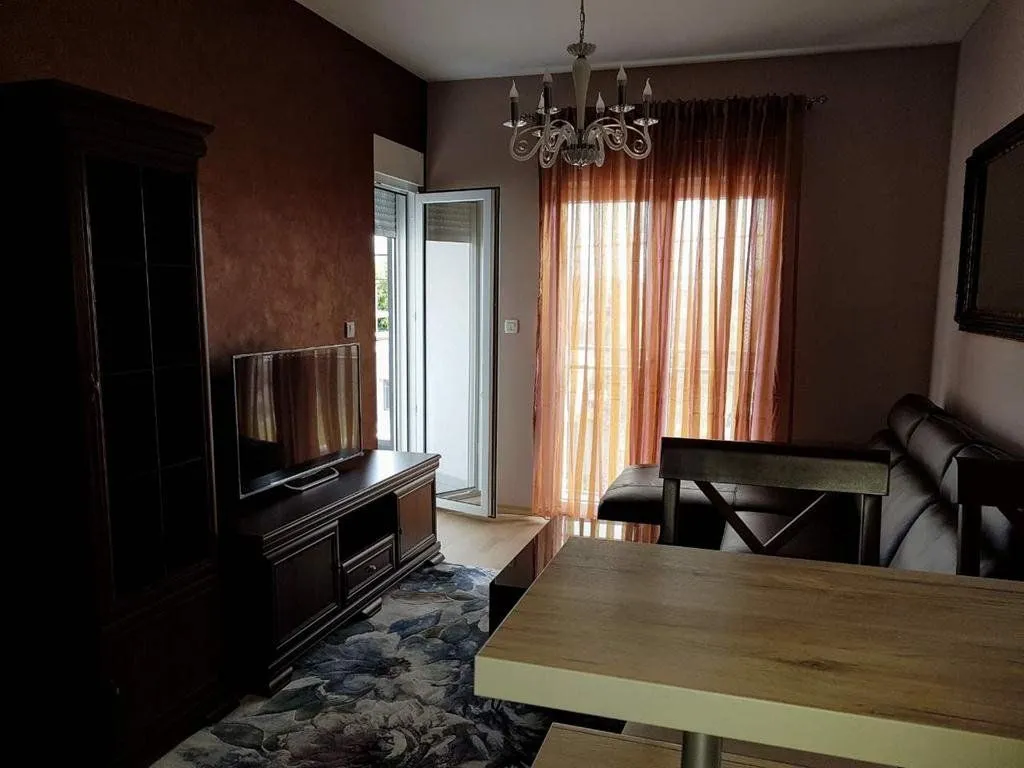 Living room with a sofa, TV, dining table and access to the balcony.