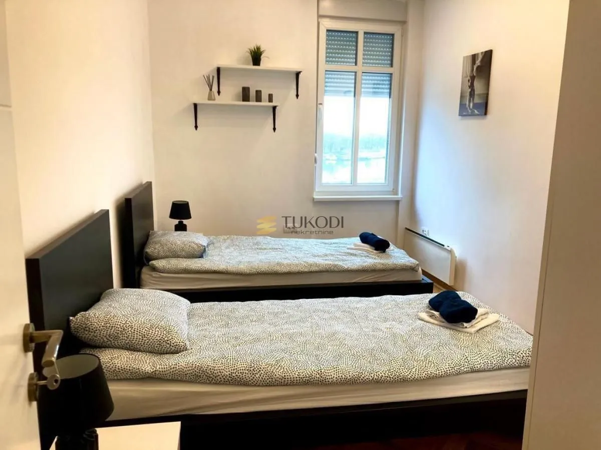 Bedroom with two single beds, a window, and wall shelves.