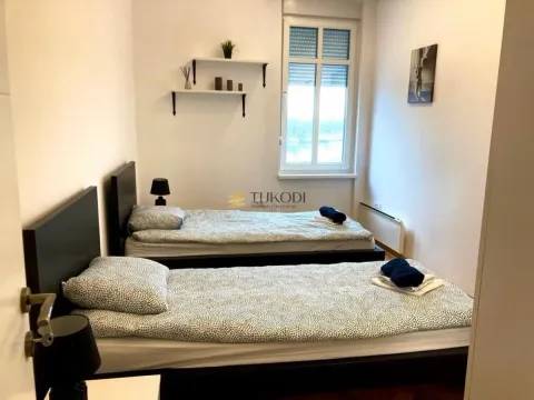 Bedroom with two single beds, a window, and wall shelves. - image 12