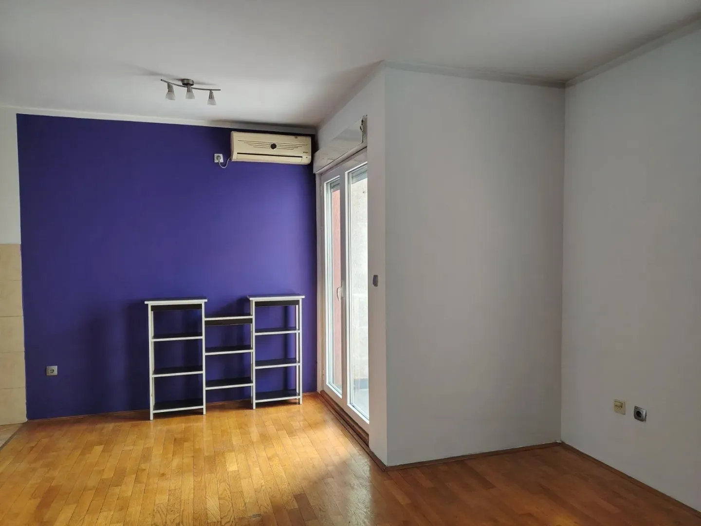 Dnevna soba sa ljubičastim zidom i drvenim podom.