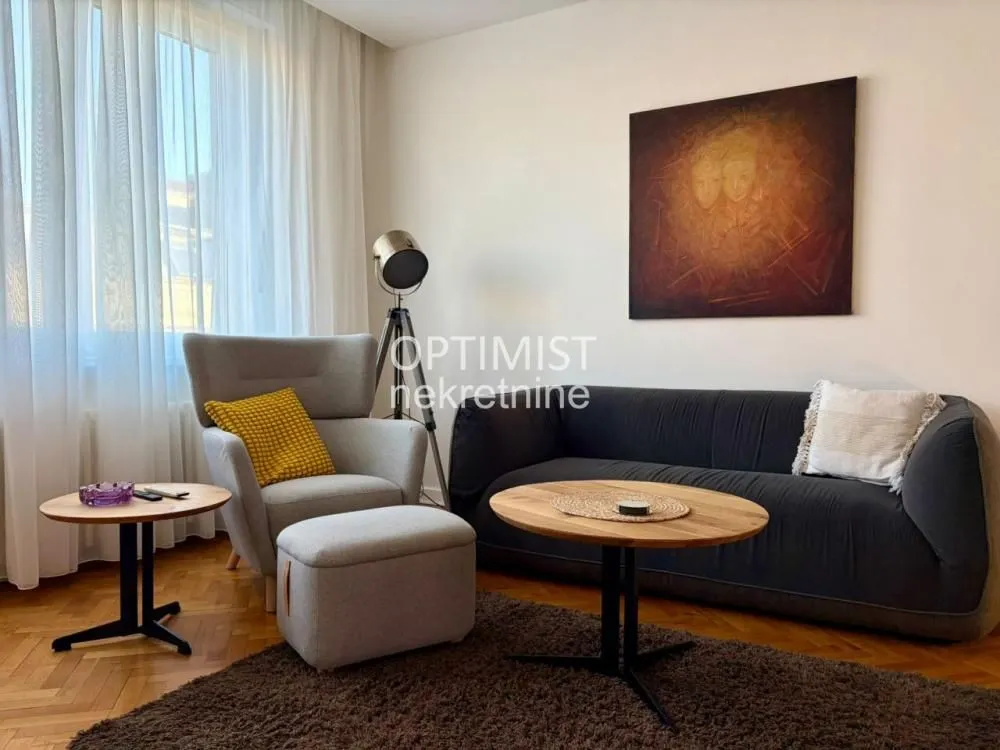 Living room with a sofa, armchair, coffee table, and an artwork on the wall.