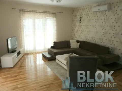 Living room with a sectional sofa, TV, and parquet flooring. - image 8
