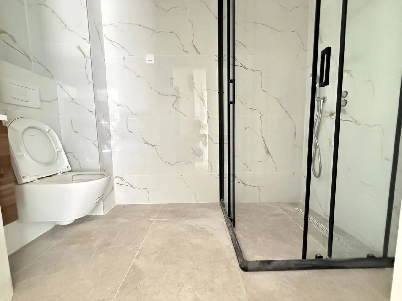 Modern bathroom with a walk-in shower and a wall-mounted toilet.