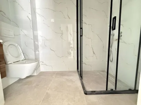 Modern bathroom with a walk-in shower and a wall-mounted toilet. - image 7