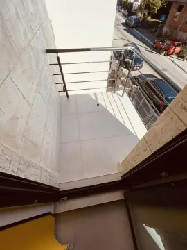 Pogled odozgo na manji popločani balkon sa metalnom ogradom i pogledom na ulicu. - image 15