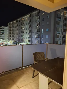 Furnished terrace with a table and chair and a view of the building at night. - image 19