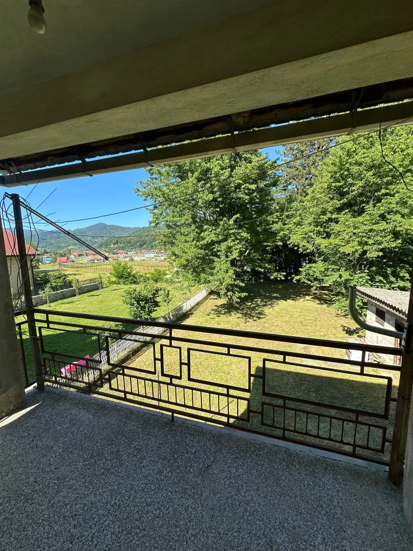 Pogled sa balkona na dvorište i okolni pejzaž.