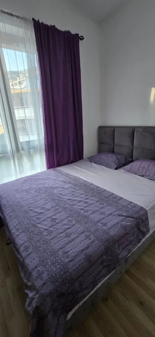 Bedroom with a double bed and purple curtains.