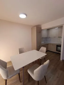 Trpezarija sa stolom i stolicama i pogledom na kuhinju u pozadini. - image 5