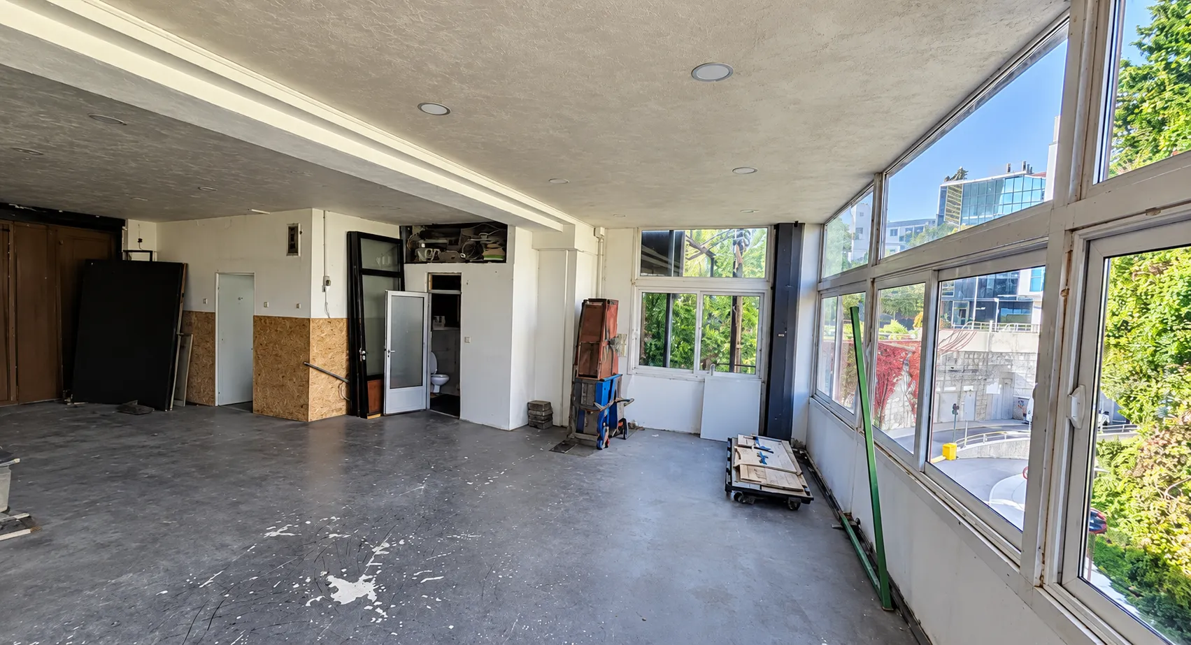 View of a large unfinished space with large windows and a tiled floor.
