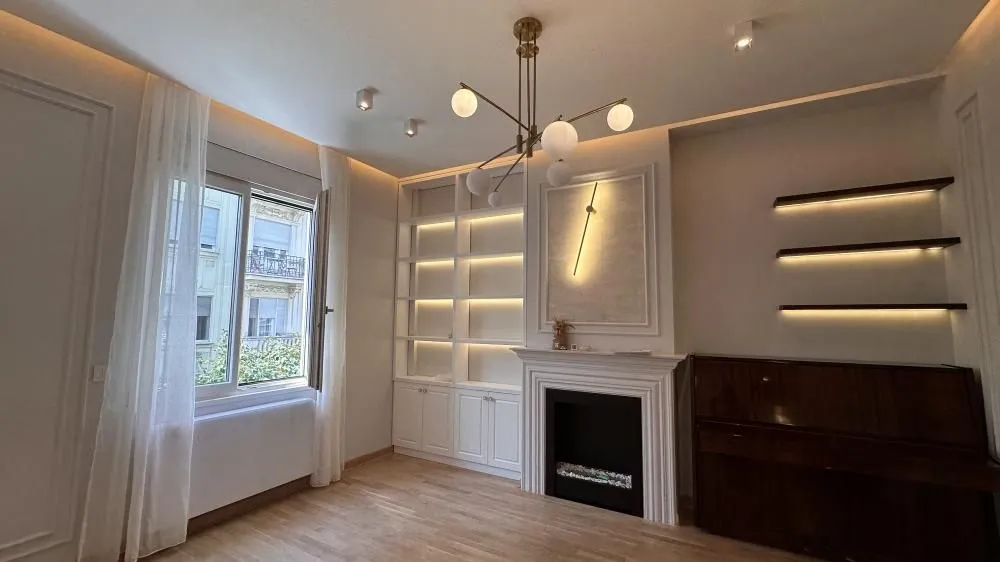 Living room with a fireplace, built-in shelves and a piano.