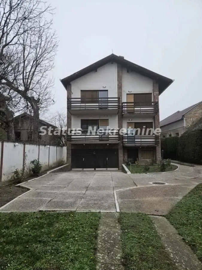 Prednji pogled na višespratnu kuću sa dvorištem i garažom.