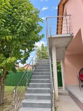 Spoljne stepenice vode na sprat kuće sa terasom i metalnom ogradom. - image 18