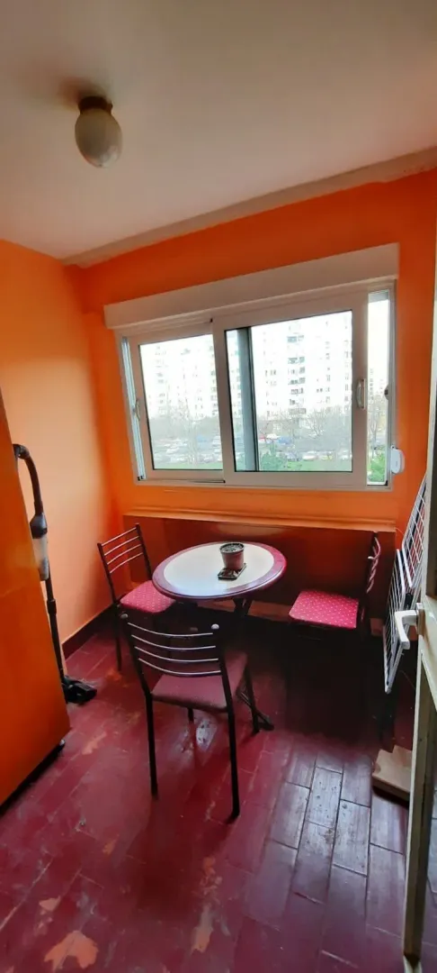 Enclosed balcony with a small dining table and chairs.