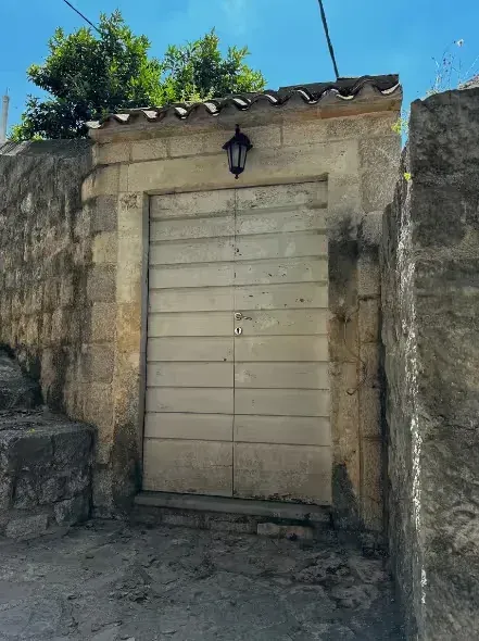 Entrance door of a traditional stone house with old lighting fixture.
