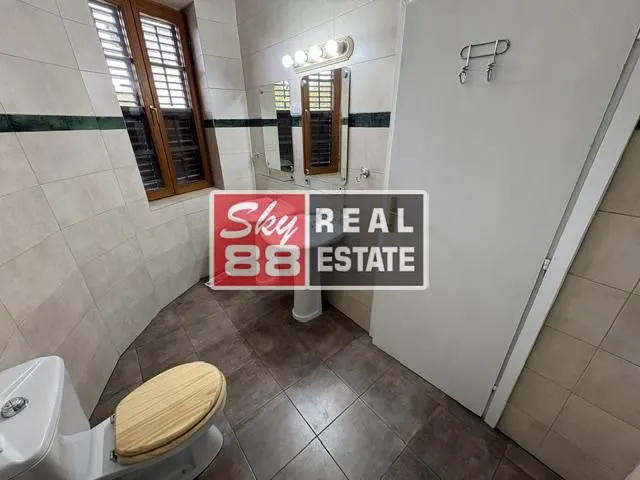 Tiled bathroom featuring a toilet, sink, and mirror.