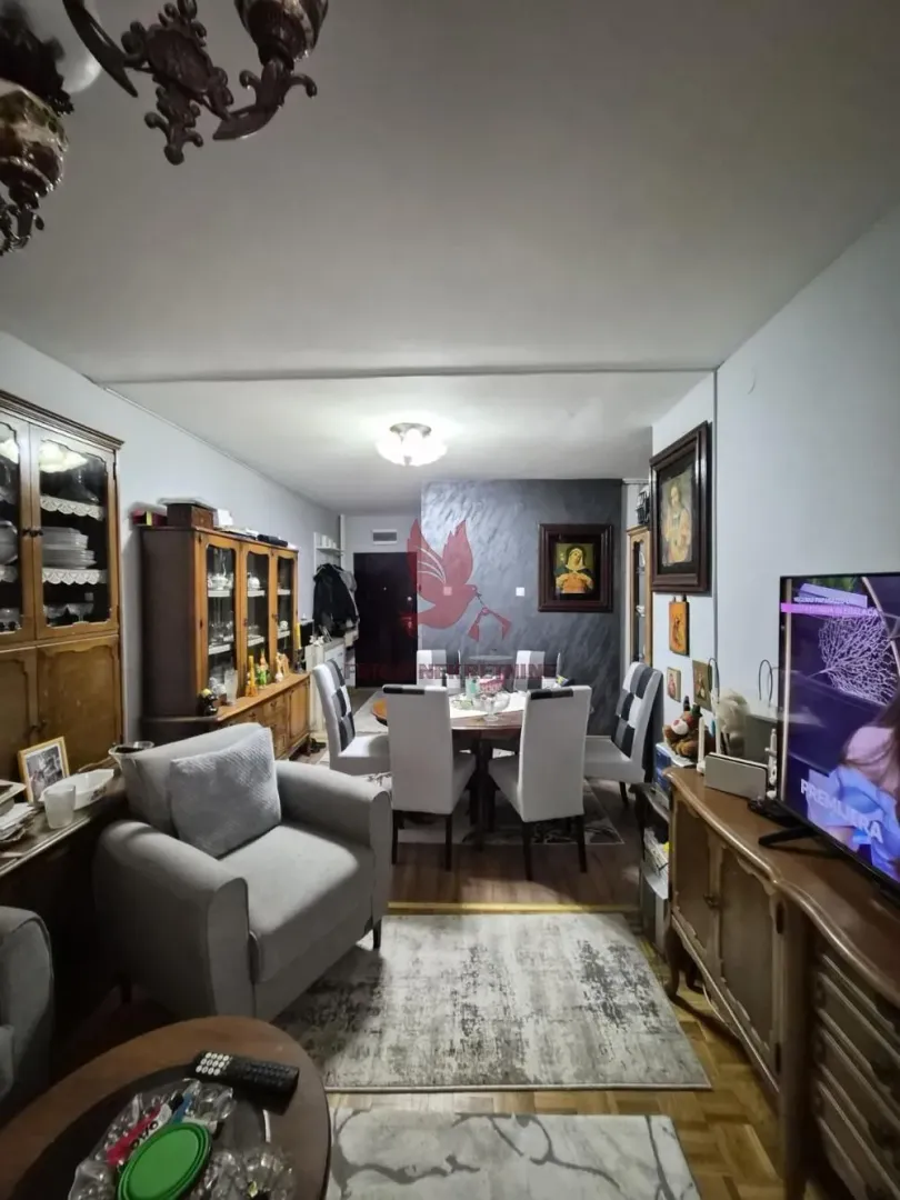 Dnevna soba sa trpezarijom, garniturom i drvenim nameštajem.
