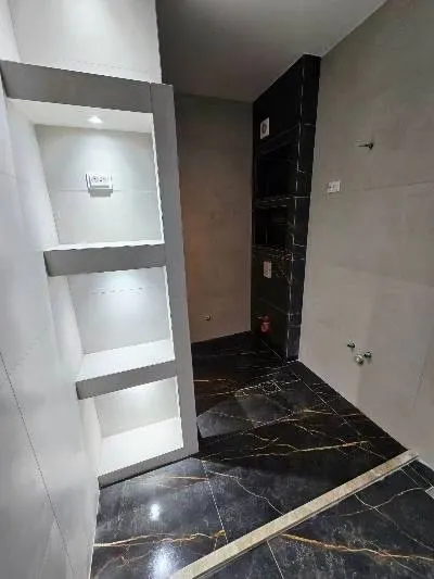 Moderne pločice i ugrađene police u kupatilu.