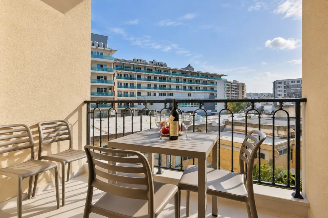 Furnished balcony with a table, chairs, and a city view.
