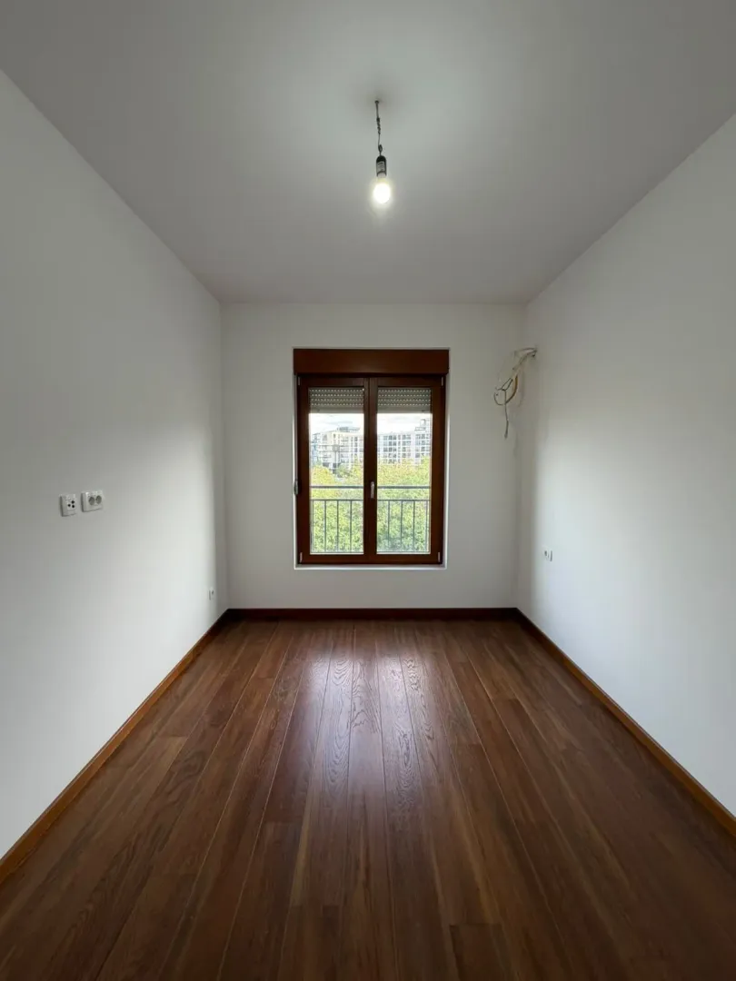 Empty room with wooden flooring and a window.