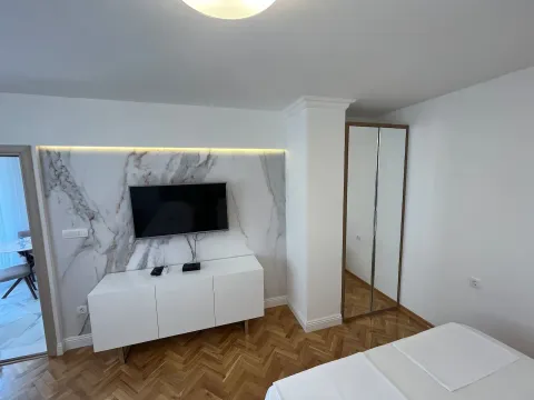 Bright bedroom with a double bed, TV, and wardrobe. - image 2