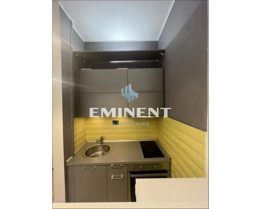 Smaller kitchen with grey cabinets and a sink.