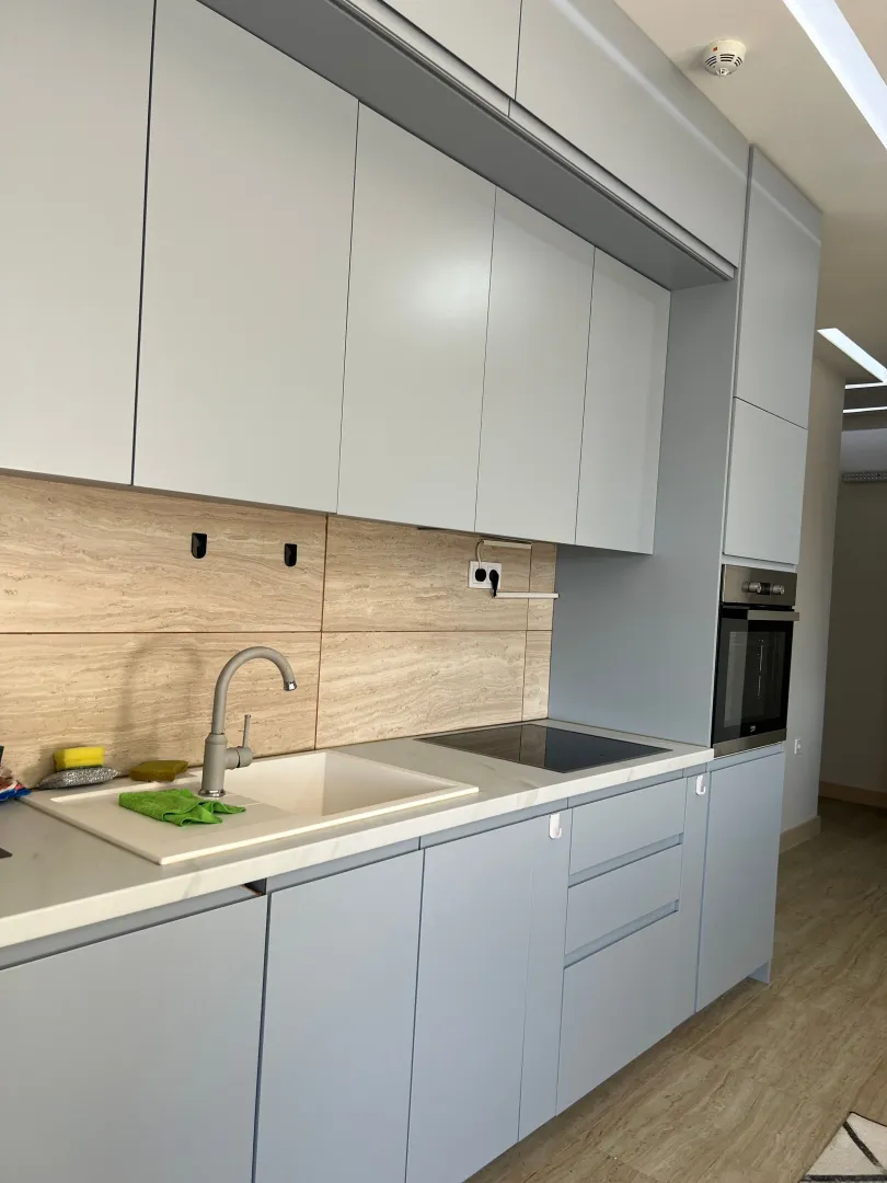 Modern light-toned kitchen with a sink and built-in oven.
