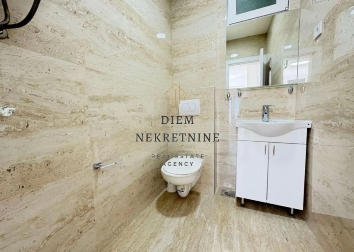 Modern tiled bathroom with a sink and toilet.