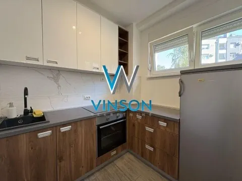 Small kitchen with white and wood-finish cabinets, a built-in oven, and a refrigerator. - image 8
