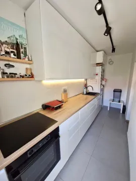 Modern kitchen with white cabinets and a wooden countertop. - image 6